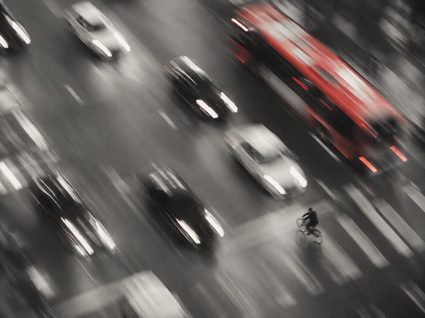 Red bus moving through city traffic, blurred with motion