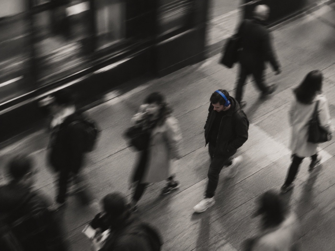 Person in blue headphones moving through a busy city street